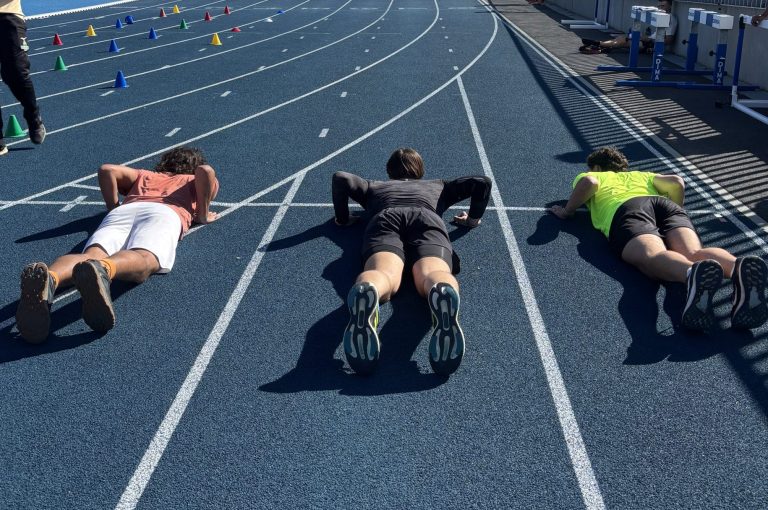 Trois athlètes en position de départ sur une piste d'athlétisme pour illustrer la préparation aux métiers du sport et au BPJEPS avec Icare.